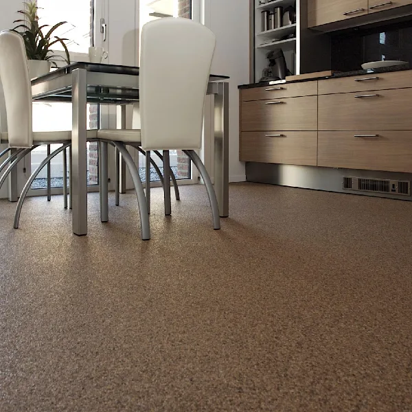 Modern kitchen with stone carpet flooring, stainless steel table and white chairs.