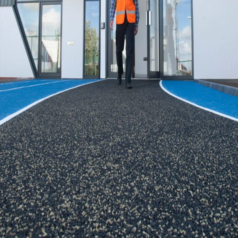 Person walking on a black and tan stone carpet walkway to the building.