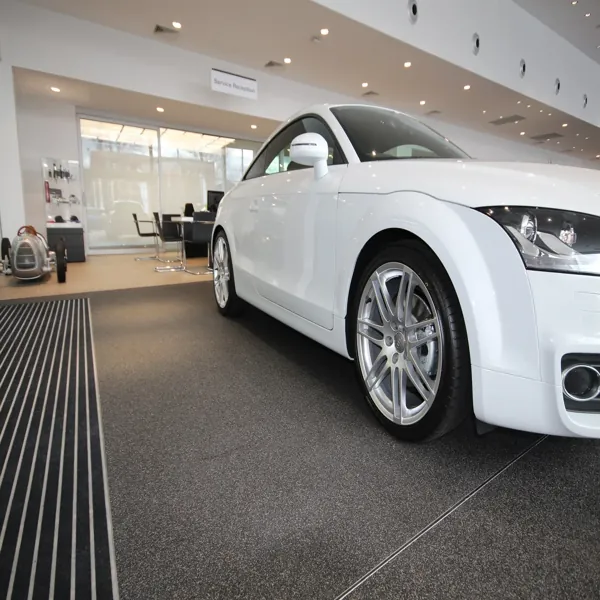 White car on a gray stone carpet floor in a car dealership.
