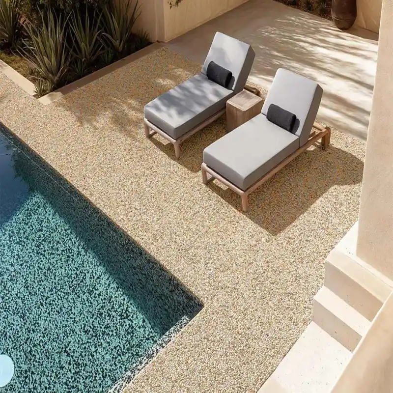 Poolside area with stone carpet flooring and two lounge chairs.