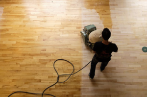 Man using a machine to sand hardwood floors